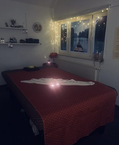 Gemütliche Zimmer mit einem Bett, Lichtern und einem Fenster zur Dämmerung.